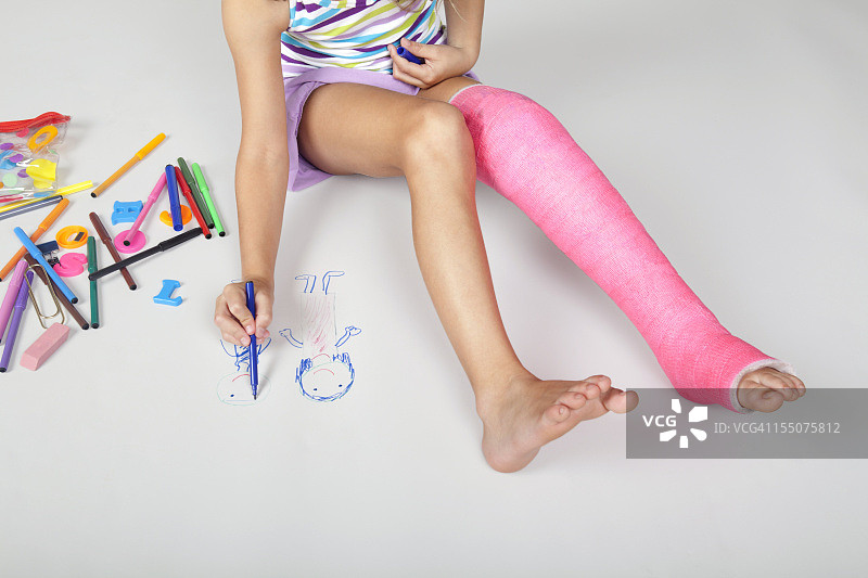 腿上打着粉色石膏的小女孩忙碌着图片素材