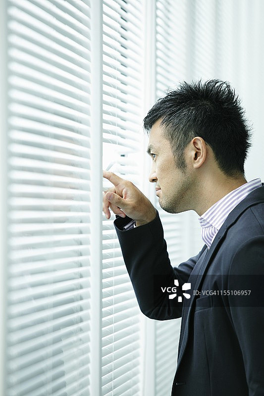 商人透过百叶窗观察，特写图片素材