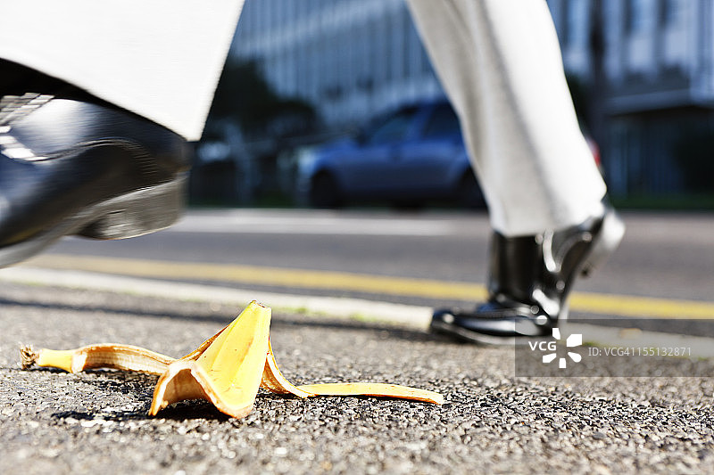 商务男人的脚踩向路上的香蕉皮图片素材