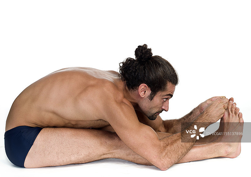 年轻男子练习比克拉姆热瑜伽前屈伸展式图片素材