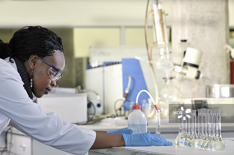 生化学家倾倒烧瓶中的液体（侧视图）图片素材