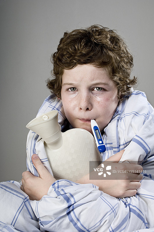 生病的孩子拿着热水瓶和体温计图片素材