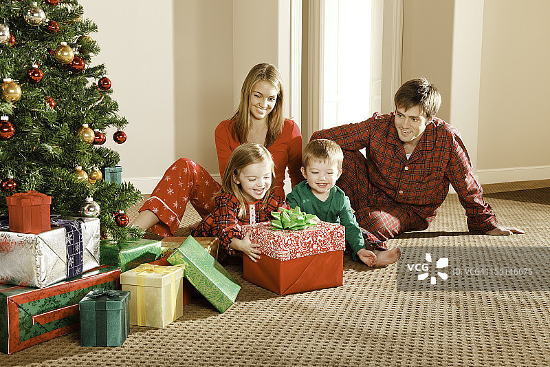 圣诞礼物早晨的兴奋，小女孩、男孩和家人打开礼物图片素材