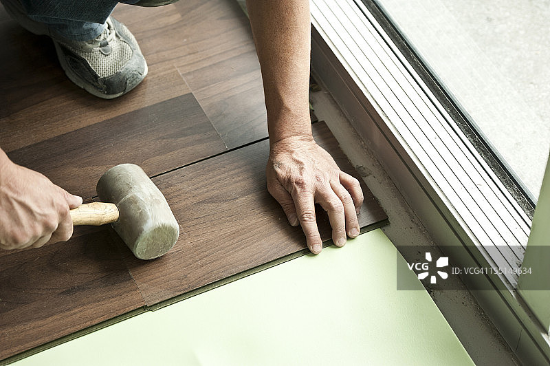 两只男人的手握着木槌安装硬木地板图片素材