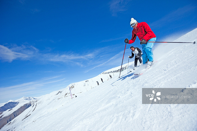 在白雪皑皑的阿尔卑斯山上滑雪的两名滑雪者图片素材