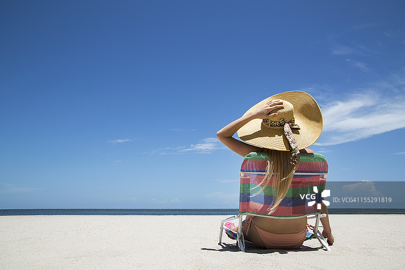 女人在沙滩的草坪椅上放松图片素材