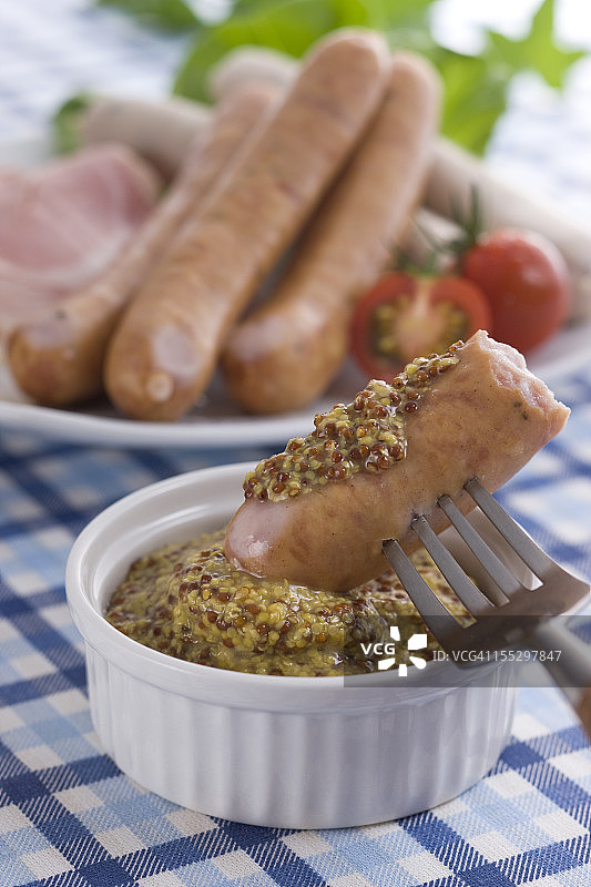 在香肠上涂抹全麦芥末酱图片素材