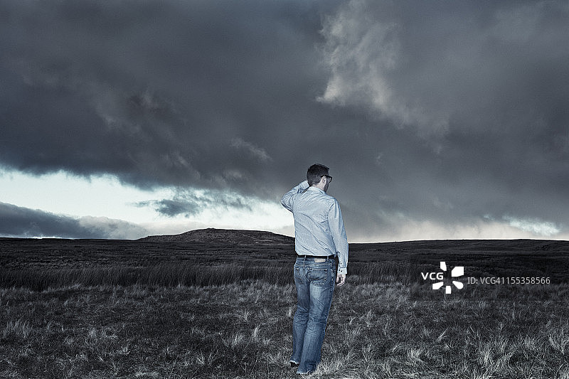 男人眺望黑暗的山坡和壮丽的天空图片素材