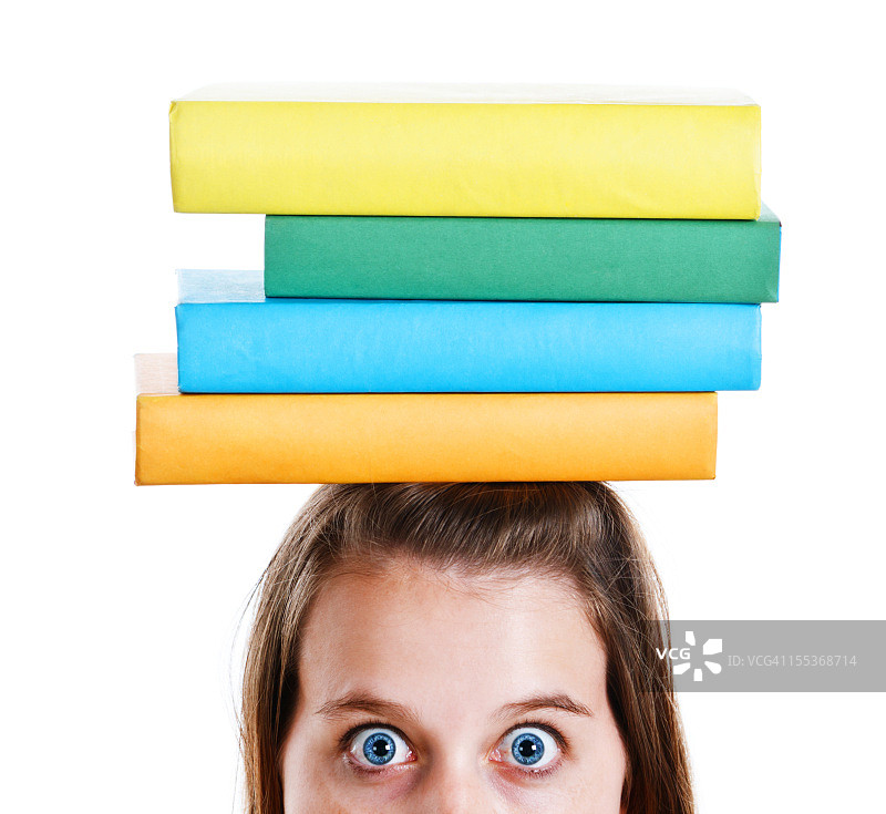 睁大眼睛的年轻女人头顶平衡着书本图片素材
