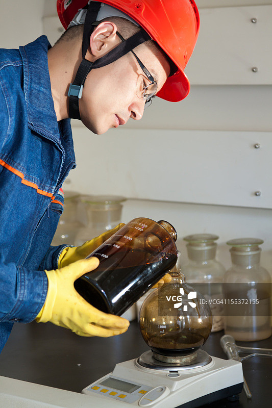 工程师将石油样品倒入实验烧瓶中图片素材