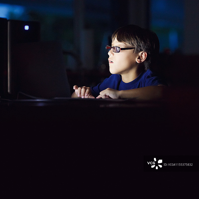 在黑暗中使用笔记本电脑的男孩图片素材