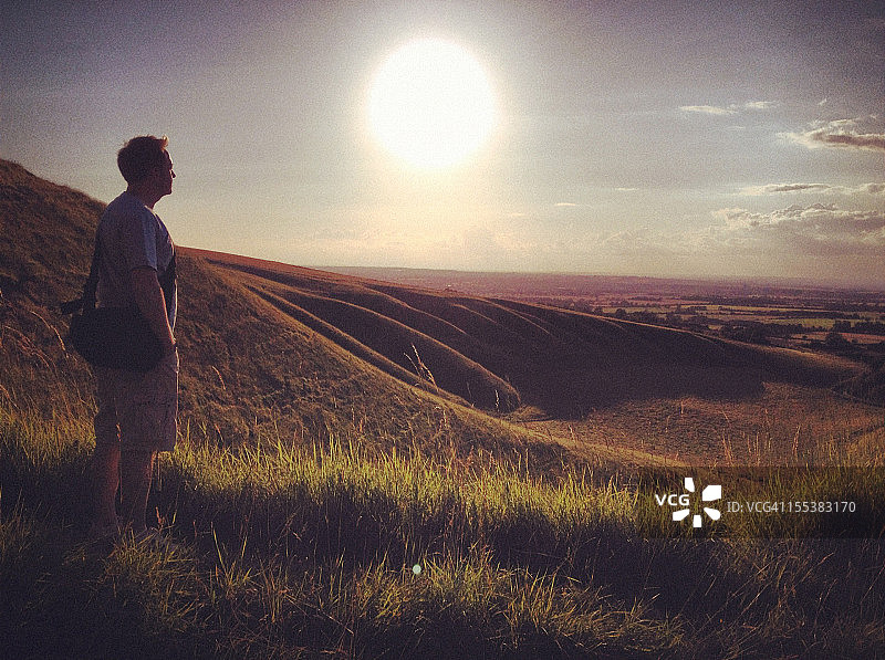 男人站在日落时分的高山草甸上图片素材