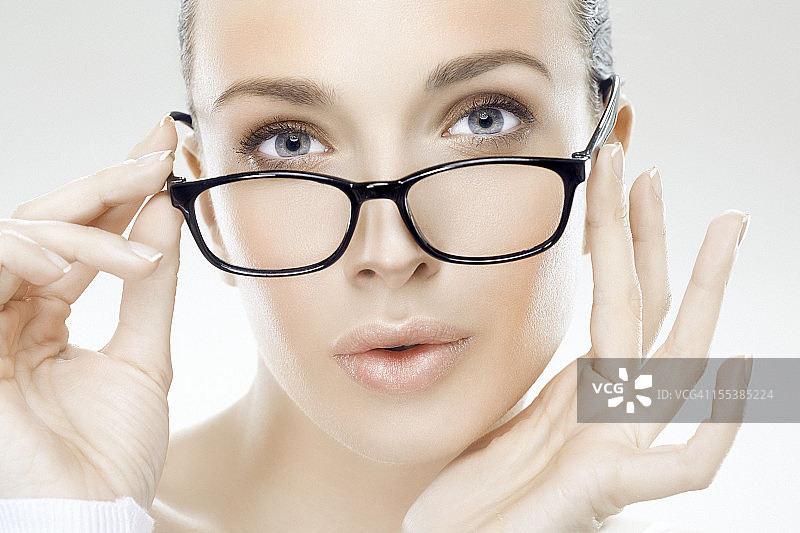手持眼镜的年轻美女面部特写图片素材