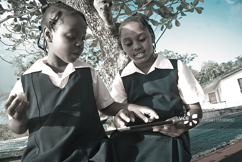 穿校服的女学生在户外使用平板电脑图片素材