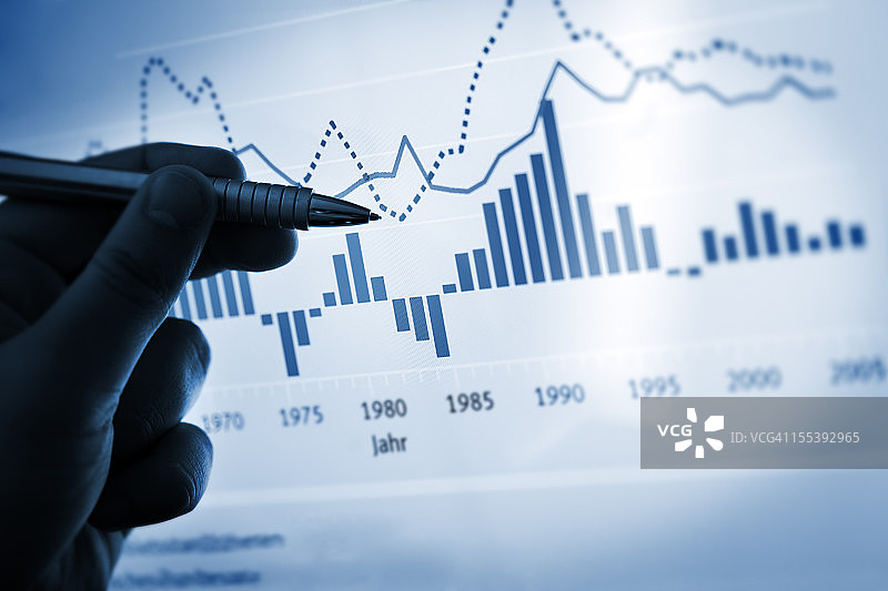 手持笔在电脑图表/文档上指点图片素材