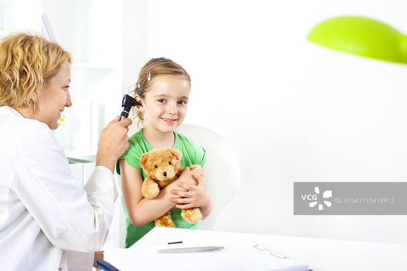 抱着泰迪熊在医生办公室的孩子图片素材