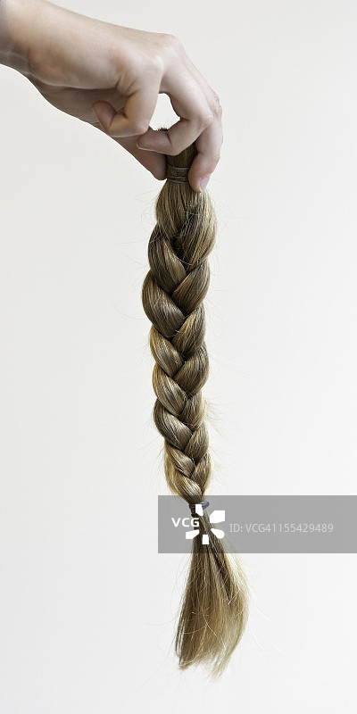 手拿编好的马尾辫，剪下来制作假发图片素材