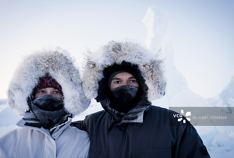 身穿极地装备的男女在冰山前合影图片素材