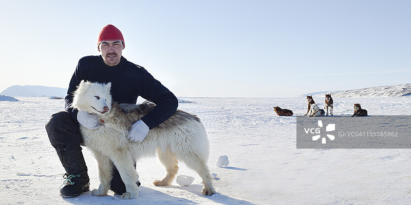 因纽特男子与北极犬在海冰上合影图片素材