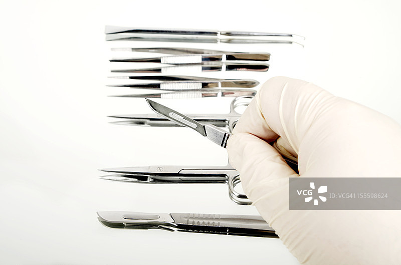 镜子上的手术器械和戴手套的手持手术刀图片素材