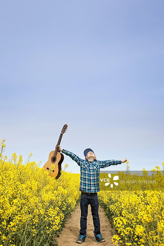 德国汉堡，男孩站在田野里抱着原声吉他图片素材