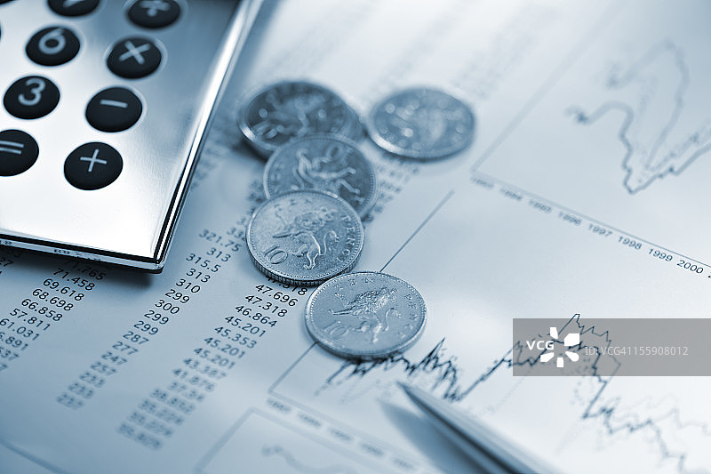 金融数据表上的银色计算器、笔和硬币图片素材
