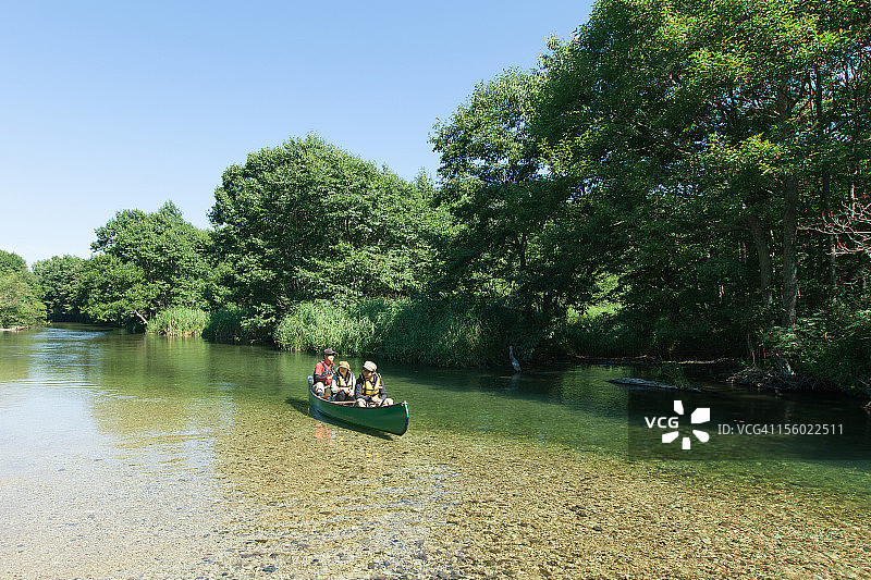 人们在日本清澈的河流上划独木舟图片素材