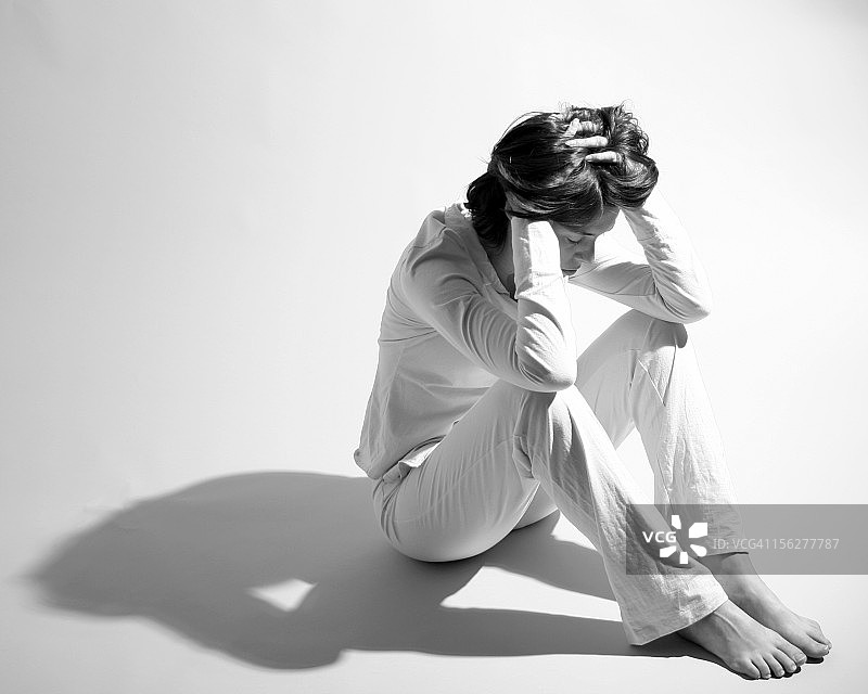 悲伤女人坐在地板上抱头图片素材