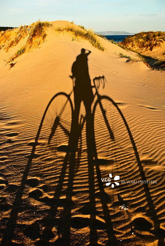 沙滩沙丘上的骑行者和自行车阴影图片素材