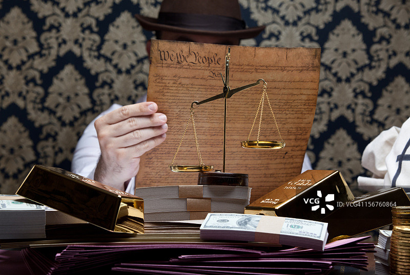男人拿着美国宪法、脏钱和金子放在桌子上图片素材