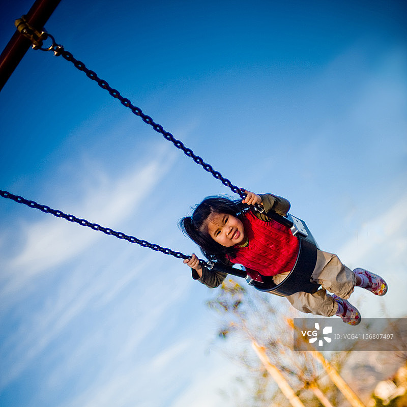 小女孩在秋千上荡得很高图片素材