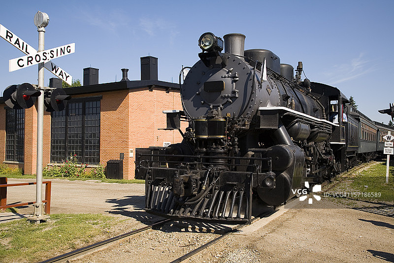 一列穿过路口的大型黑色蒸汽火车图片素材