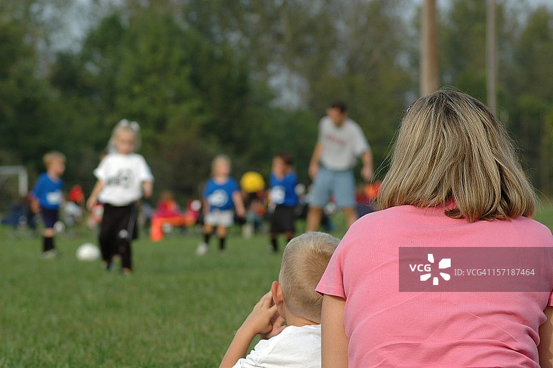 妈妈和兄弟观看姐妹踢足球比赛图片素材