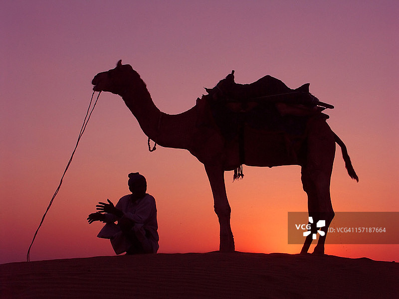 斋沙默尔沙丘日落时分的骆驼和骑手图片素材