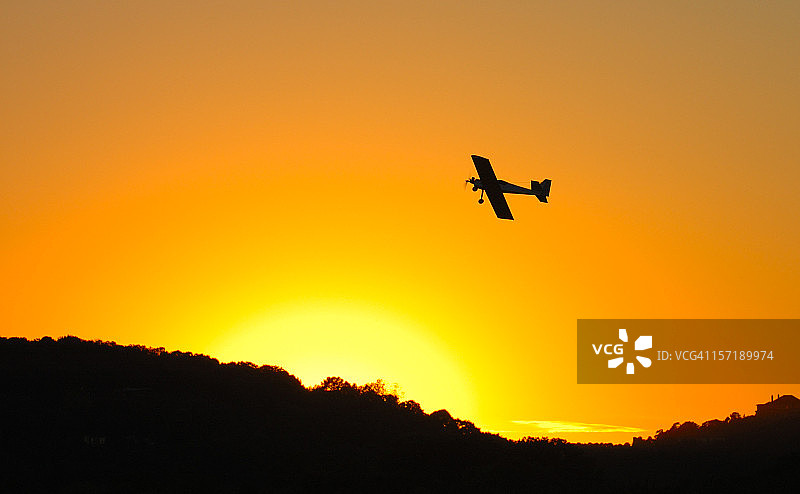 日落时分橙色天空中的飞机底部图片素材