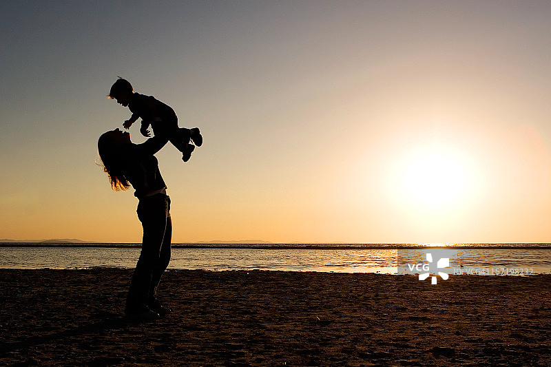 母亲抱着孩子在阳光明媚的泳池边图片素材