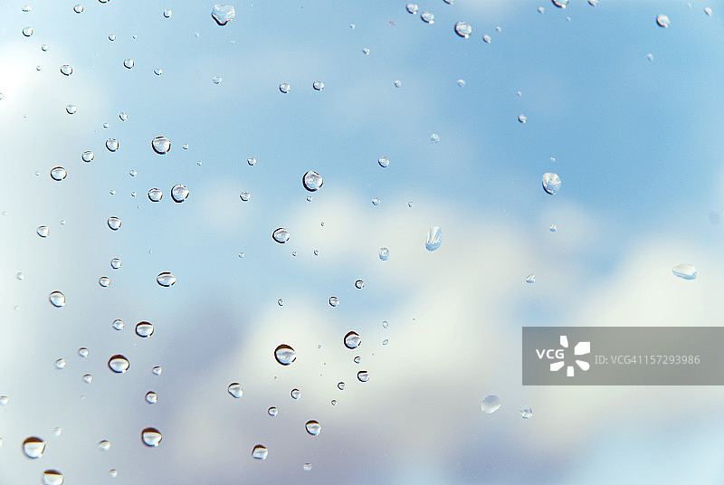 窗户上的雨滴，背景是云朵和蓝天图片素材