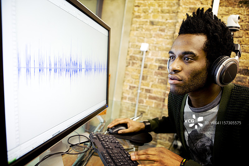 现代工作场所：音频工程师在其计算机上编辑波形图片素材