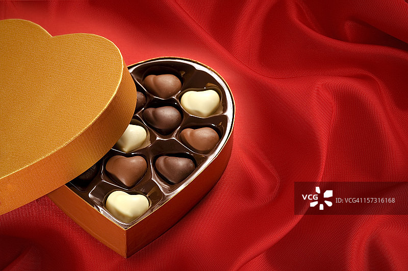 红色缎面背景上的金色巧克力礼盒图片素材