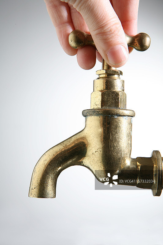 一只手放在水龙头上，象征着缺水图片素材