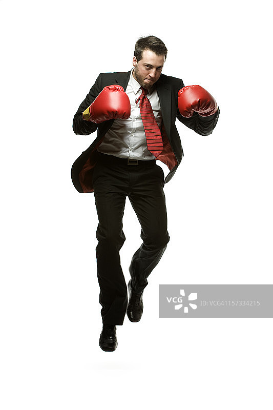 穿着深色西装，戴着红色拳击手套跳跃的商人图片素材