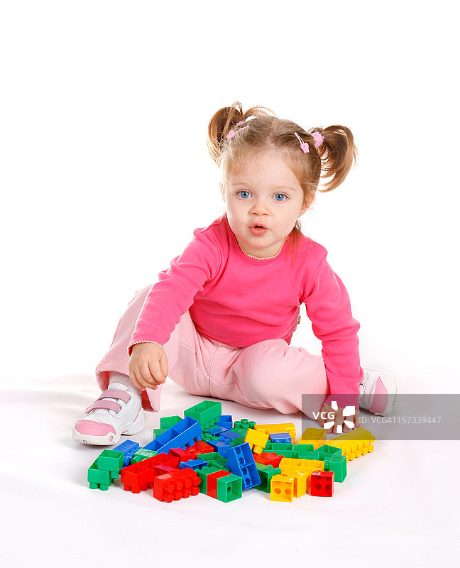 可爱的小女孩在白色背景上玩积木图片素材