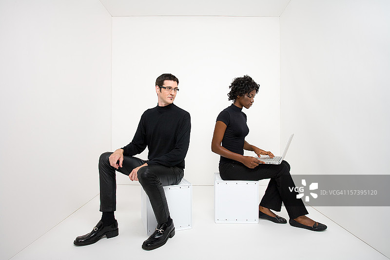 男子看着使用笔记本电脑的女人图片素材