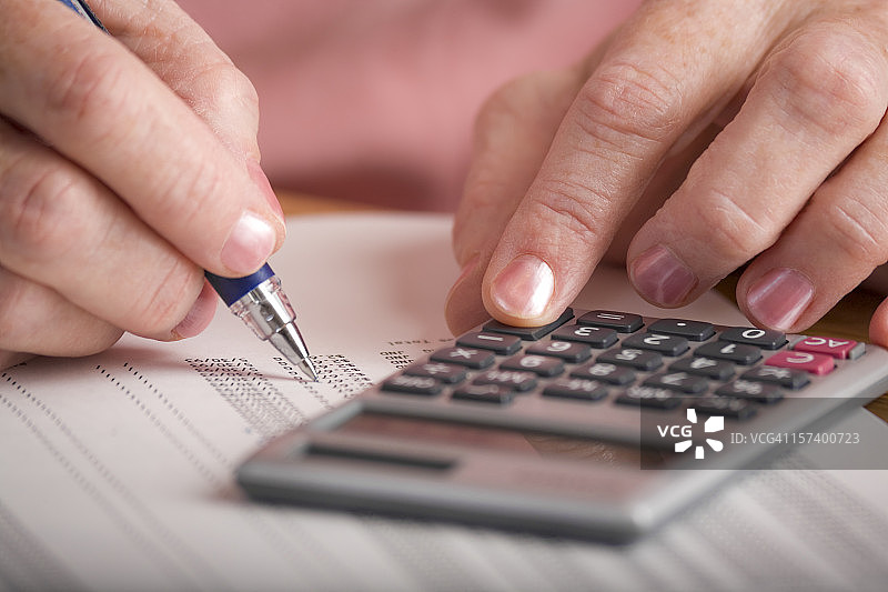 中年妇女使用计算器审核数据打印稿图片素材