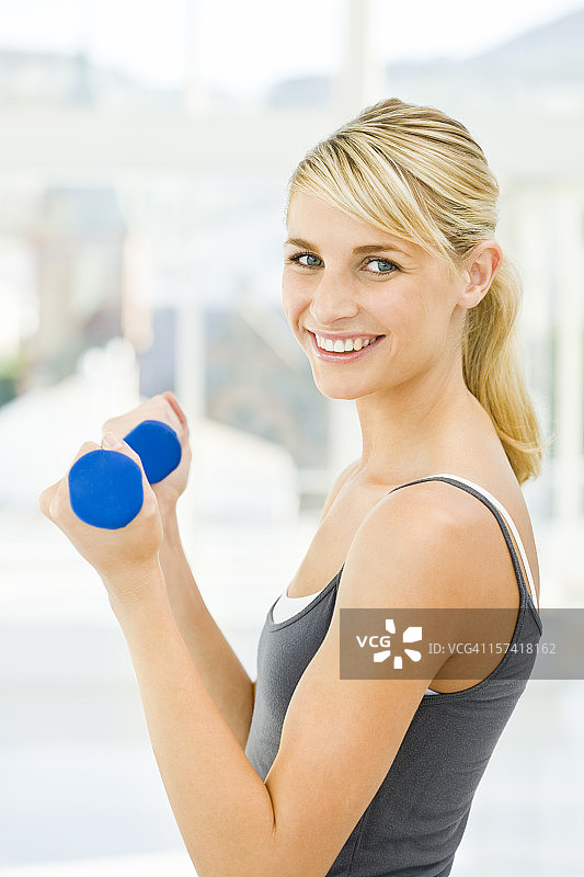 拿着哑铃微笑的年轻女人图片素材