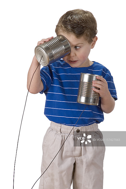 困惑的男孩看着一个罐头电话图片素材