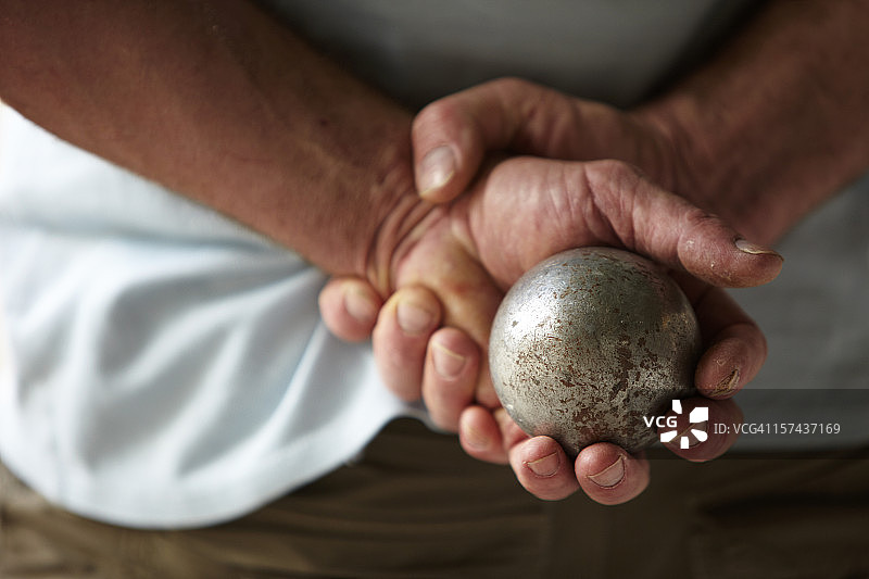 双手背后拿着金属球的年长男人图片素材