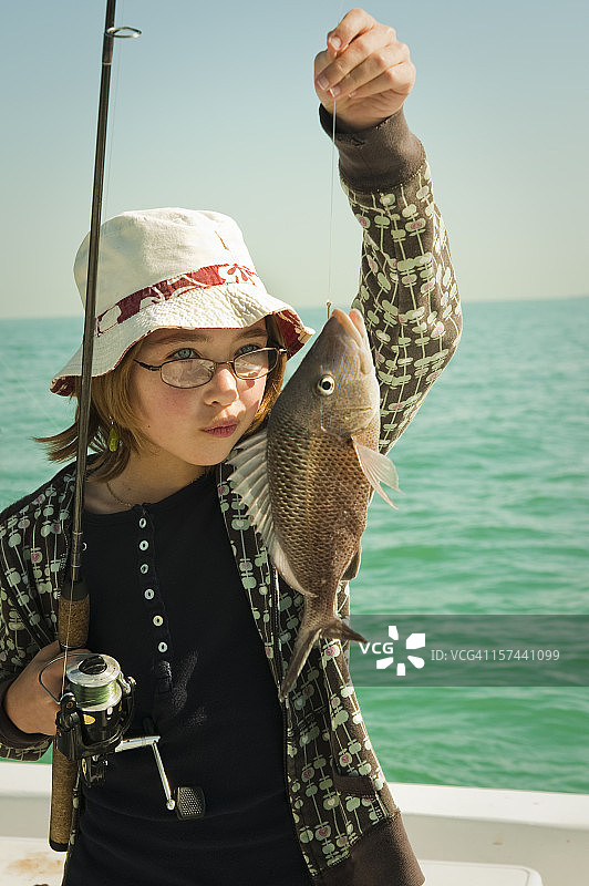 可爱的年轻女孩钓到一条好鱼，竖版照片。图片素材