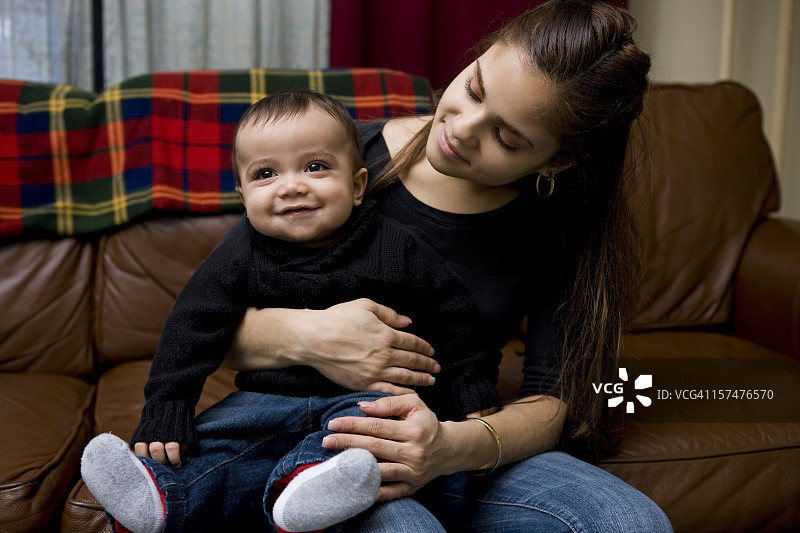 可爱的男婴坐在拉丁裔母亲的腿上图片素材