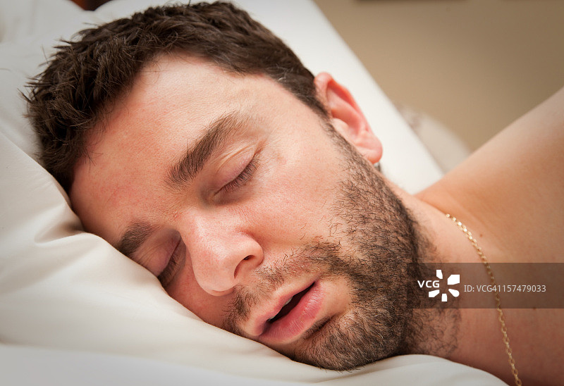 一位留着胡子的年轻人在床上熟睡的特写镜头图片素材